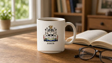 
Wczytaj obraz do galerii, White 11oz Heritage Mug with the Baker coat of arms and surname on a wooden desk by a window (illustrative photo)
